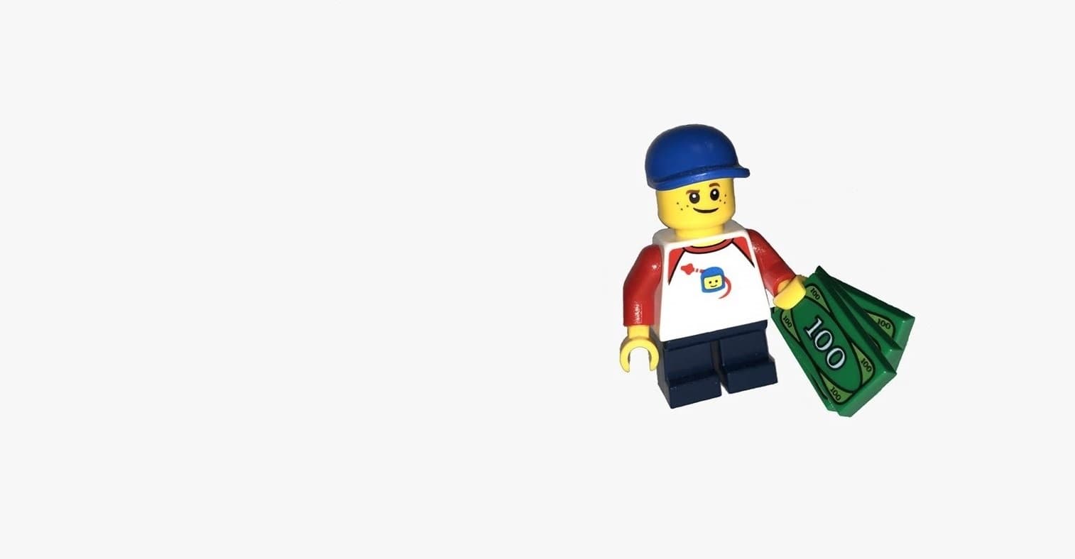 A LEGO boy holding some LEGO banknotes.